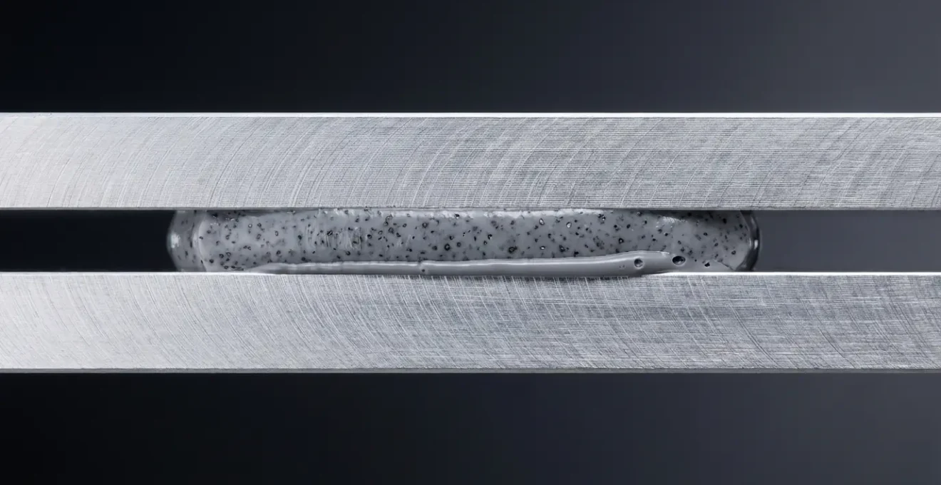 Vue en coupe d'un matériau d'interface thermique appliqué entre deux surfaces métalliques montrant l'élimination des micro-bulles d'air