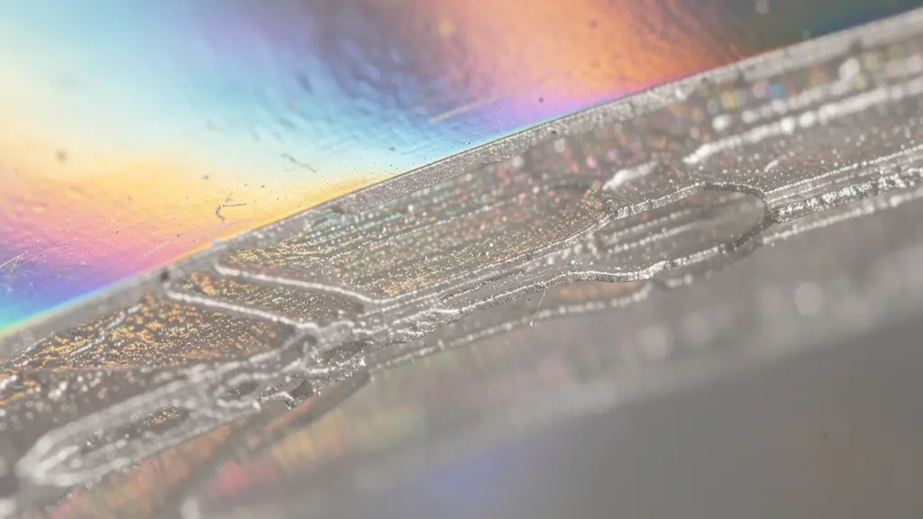 Vue macro d'un film métallique ultra-mince déposé sur substrat polymère flexible avec effet iridescent
